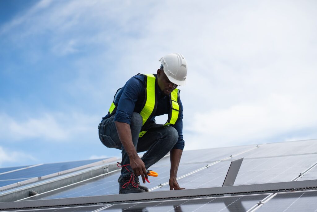 Técnico instalando y ajustando paneles solares en cubierta plana.